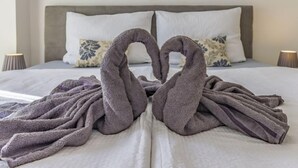 A neatly made bed with two towels arranged in a heart shape.