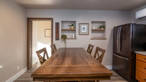 A modern kitchen with a wooden dining table, built-in shelves, and a stainless steel refrigerator. - Tumalo House (Bend)