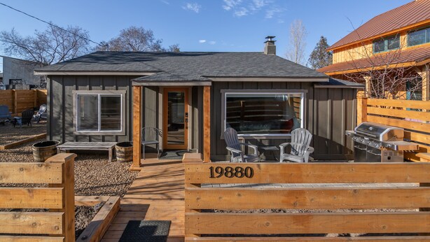A wooden cabin with a number '19880' on the front, a patio with outdoor seating, and a grill. - Tumalo House (Bend)