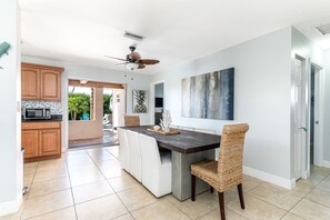 A modern kitchen with a central island, wooden cabinets, and a ceiling fan.