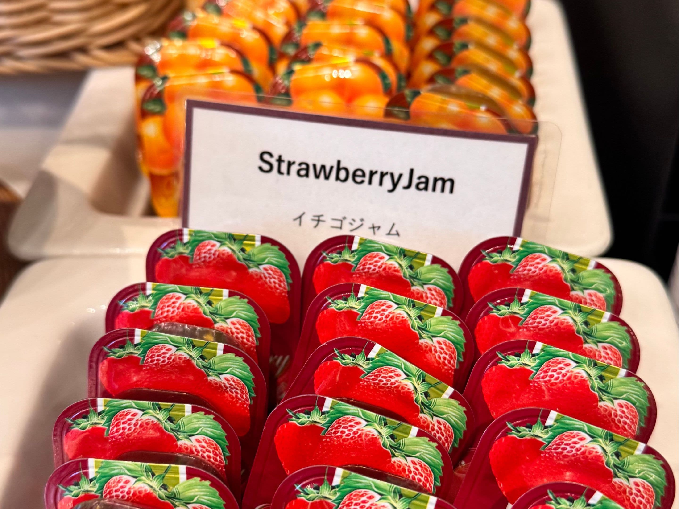 A display of strawberry jam containers with a sign above them.