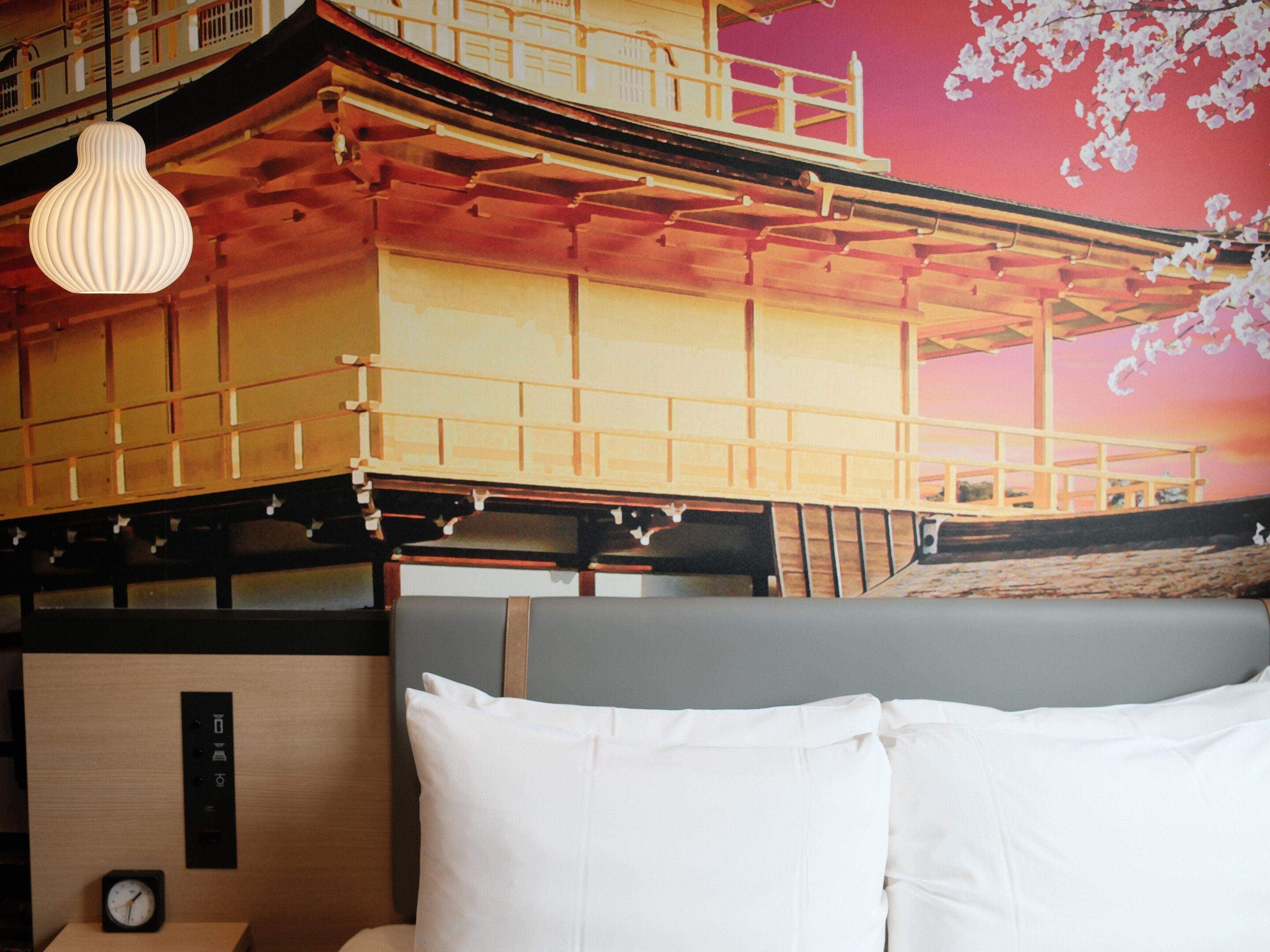 A hotel room with a traditional Japanese-style interior, including a tatami mat floor, a low wooden bed, and a view of a wooden structure with a balcony.