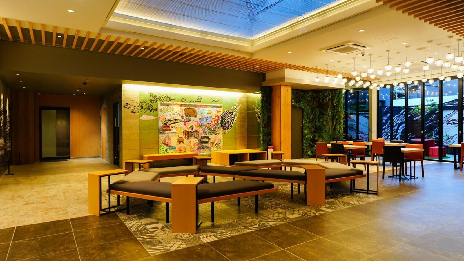 A modern lobby with seating areas, a colorful mural, and large windows.