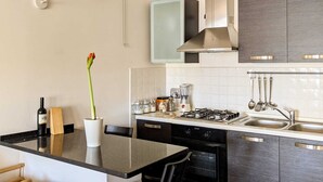 Une cuisine moderne dotée d’un plan de travail noir, d’appareils électroménagers en acier inoxydable et de meubles de rangement gris.