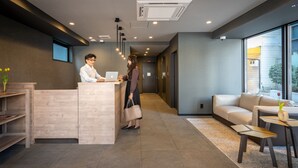 A reception area with a reception desk, a sofa, and a small table with a vase. - BON Kyoto Kiyomizu (Kyoto)