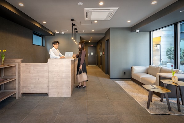 A reception area with a reception desk, a sofa, and a small table with a vase.