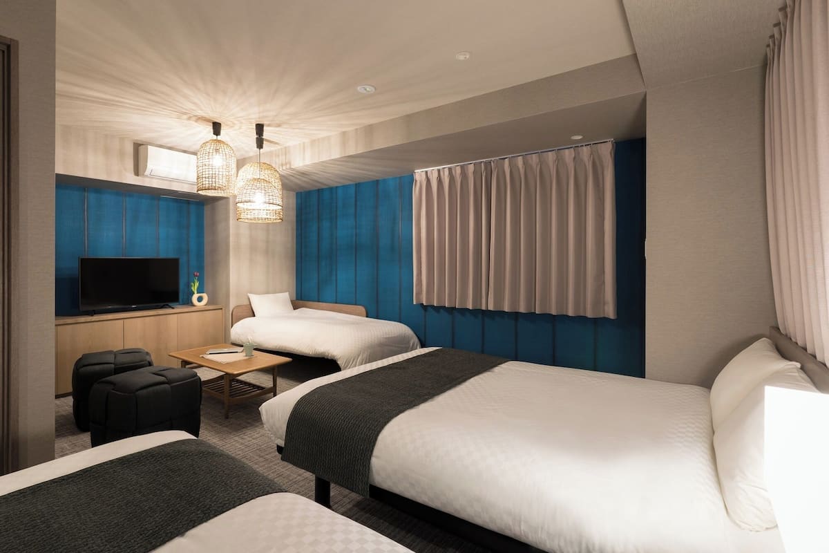 Une chambre d’hôtel avec deux lits, une télévision, un bureau et un coin salon.
