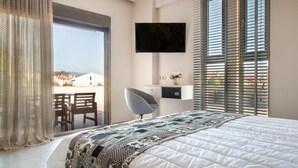 Un dormitorio moderno con una cama grande, un televisor de pantalla plana montado en la pared, un escritorio con una silla y vistas a través de la ventana.