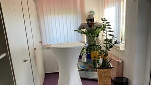 A room with a white table, a potted plant, and a purple carpet.