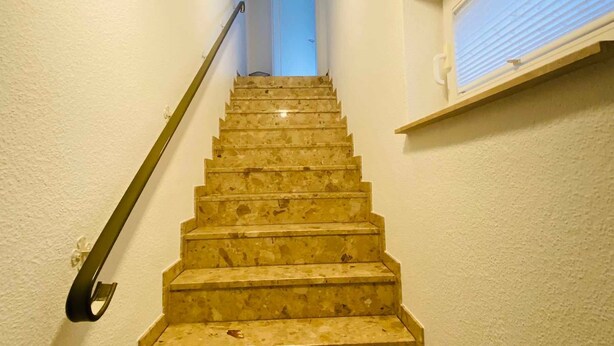 A staircase with a handrail, leading to a door at the top.
