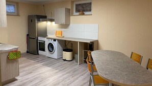 A compact kitchen with a washing machine, a refrigerator, and a dining area with chairs.