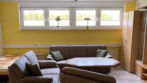A living room with a brown sofa set, a coffee table, and a window with two potted plants.