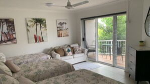 A bedroom with two beds, a ceiling fan, and a sliding glass door leading to a balcony. - BEACH, SHOPS & STRAND 5 min walk away (North Ward)