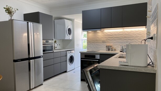 A modern kitchen with stainless steel appliances, a built-in oven, a washing machine, and a dishwasher. - BEACH, SHOPS & STRAND 5 min walk away (North Ward)