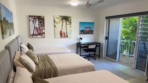 A bedroom with two beds, a desk, and a balcony with a view of greenery. - BEACH, SHOPS & STRAND 5 min walk away (North Ward)