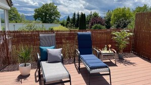 A deck with two lounge chairs, a small table, and a potted plant.