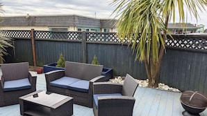 Eine Terrasse im Freien mit Korbmöbeln, einem kleinen Tisch und einer dekorativen Schale.