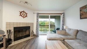 A living room with a fireplace, a sofa, a coffee table, and a balcony with a view.