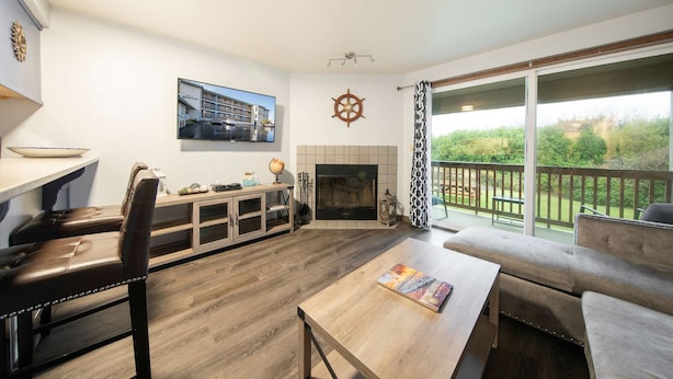 A living room with a fireplace, a television mounted on the wall, a dining table, and a sofa.