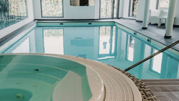 Una piscina interior con un jacuzzi, agua cristalina y un borde empinado de azulejos.