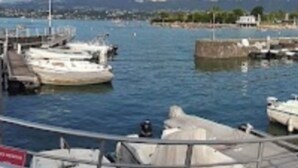 Un puerto deportivo con barcos amarrados, cielo despejado y montañas al fondo.