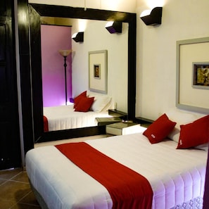 Quarto de hotel com cama grande, mesa de cabeceira, espelho e uma obra de arte na parede.