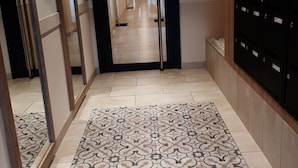 A hallway with patterned flooring, a mirror, and a row of black lockers on the right. - Superb T3 apartment in a quiet location overlooking the port of Crouesty (Arzon)