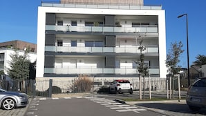 A modern multi-story residential building with balconies, a parking area, and a clear blue sky. - Superb T3 apartment in a quiet location overlooking the port of Crouesty (Arzon)