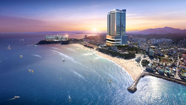 A coastal cityscape with a prominent high-rise hotel, a beach, and a pier. - Hotel the Blue Terra (Sokcho)