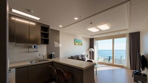 A modern kitchen with a central island, bar stools, and a built-in oven. - Hotel the Blue Terra (Sokcho)