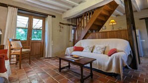 Une pièce chaleureuse avec un escalier en bois, un canapé avec des coussins, une table en bois et une chaise.