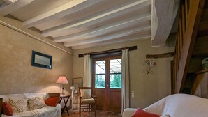 Un salon confortable avec un canapé, un fauteuil, une table basse et une fenêtre avec des rideaux.