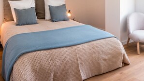 Un dormitorio con cama, almohadas, una mesita de noche y una silla.