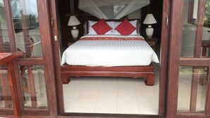 Een bed met wit beddengoed en rode kussens, een houten hoofdbord en twee bedlampen.