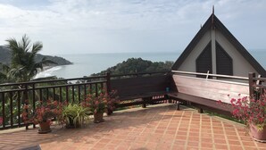 Een balkon met uitzicht op zee en een bergachtig landschap.