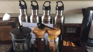 Een koffiehoek met roestvrijstalen thermoskannen, een koffiemolen en potten met koffie en room.