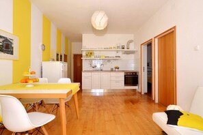 A compact kitchen with white cabinets, a wooden countertop, and a hanging light fixture.