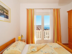 A bedroom with a bed, a nightstand, a lamp, and a view of the sea through a balcony door. - Stunning Apartment in Bol (Bol)