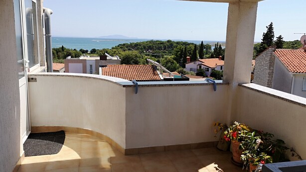 Ein Balkon mit Meerblick, Fliesenboden und Blumentöpfen.
