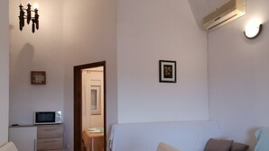 Ein kompakter Wohnraum mit Küchenzeile, einem Essbereich und einer Sitzecke mit Sofa und Sesseln.