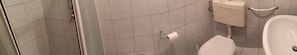 Une salle de bain comprenant des toilettes, un lavabo et un espace douche.
