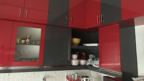 A kitchen with red and black cabinets, a white countertop, and various kitchen items. - Stunning 2-bed Apartment in Thiruvananthapuram (Thiruvananthapuram)