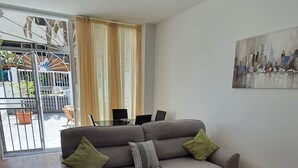 Ein Wohnzimmer mit einem grauen Sofa, einem Glastisch und einem Bild an der Wand.