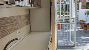 Eine moderne Küche mit Spüle aus Edelstahl, Holzschränken und Blick auf die Terrasse.
