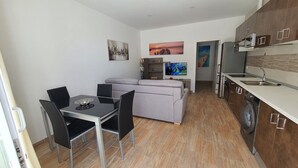 Eine moderne Wohnung mit Essbereich, Sofa, Küche und Fernseher.