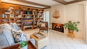 Un salon chaleureux avec une cheminée, une bibliothèque, un canapé confortable et une table basse.