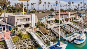 Une maison de vacances dans les Keys, avec un voilier amarré, un espace de détente extérieur abrité et une vue sur le quartier résidentiel environnant.