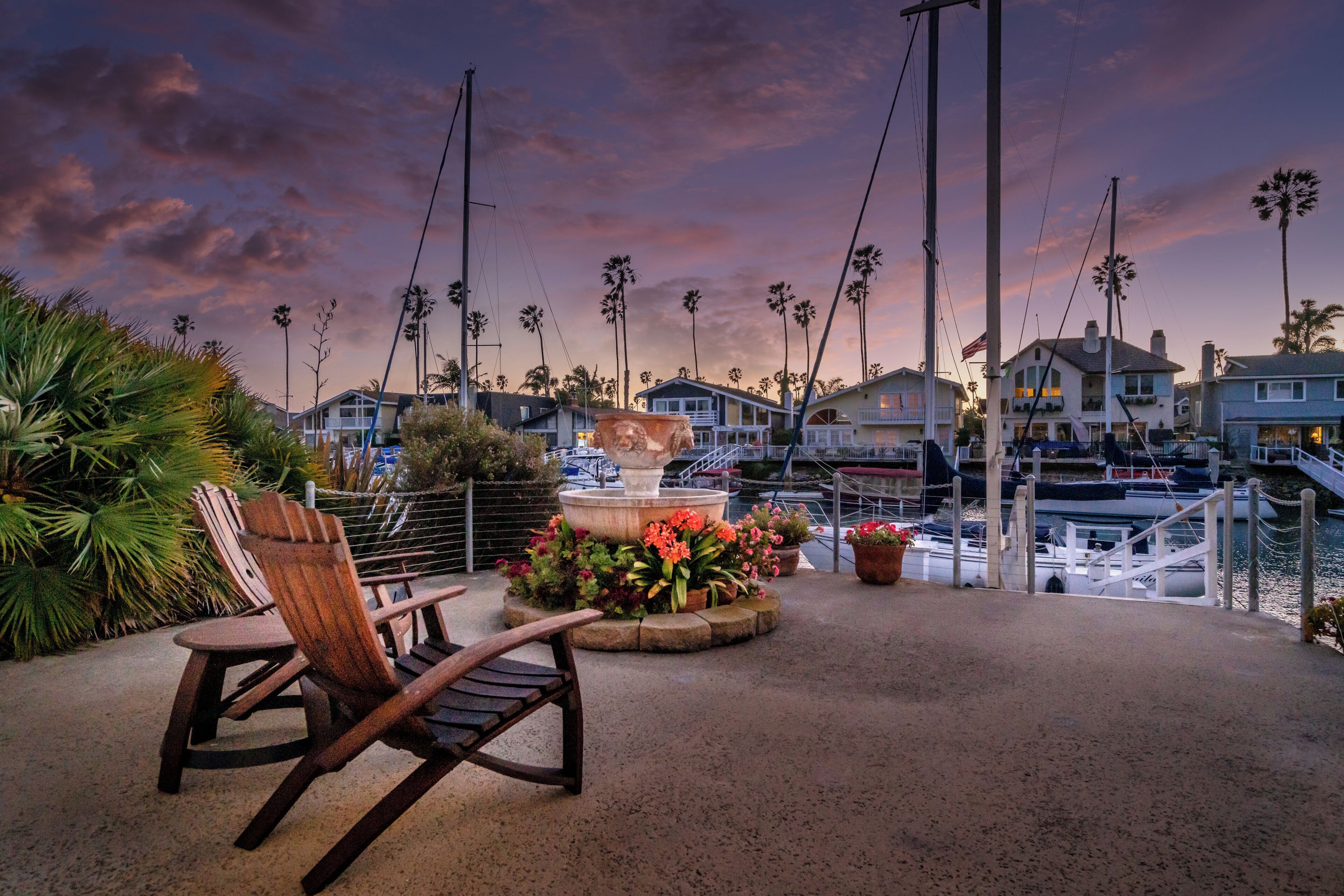 Un patio frente al agua con una silla, una fuente y vistas a barcos y casas.