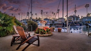Une terrasse au bord de l’eau, avec une chaise, une fontaine et une vue sur les bateaux et les maisons.