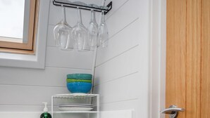 A kitchen with a white countertop, a wooden door, and a shelf with various kitchenware. - Dragonfly - sleeps 2 guests  in 1 bedroom (Norwich)
